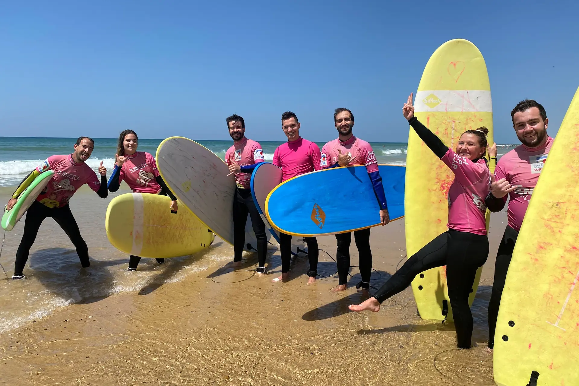 Seven trainees from the Tengo Frio Surfschool in Lacanau posing on the sand